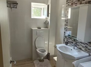 Un baño con inodoro, lavamanos, espejo y ventana.