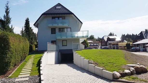 A modern two-story house with a balcony, a paved driveway, and a well-maintained lawn. - Ferienresidenz Hinterzarten FEWO H12 (Hinterzarten)