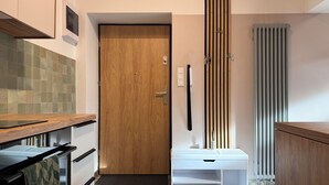 A modern kitchen with a wooden door, a white cabinet, and a patterned floor. - Cozy Apartment 3 min from Main Station Old Town Quiet Dapartments.eu (Kraków)