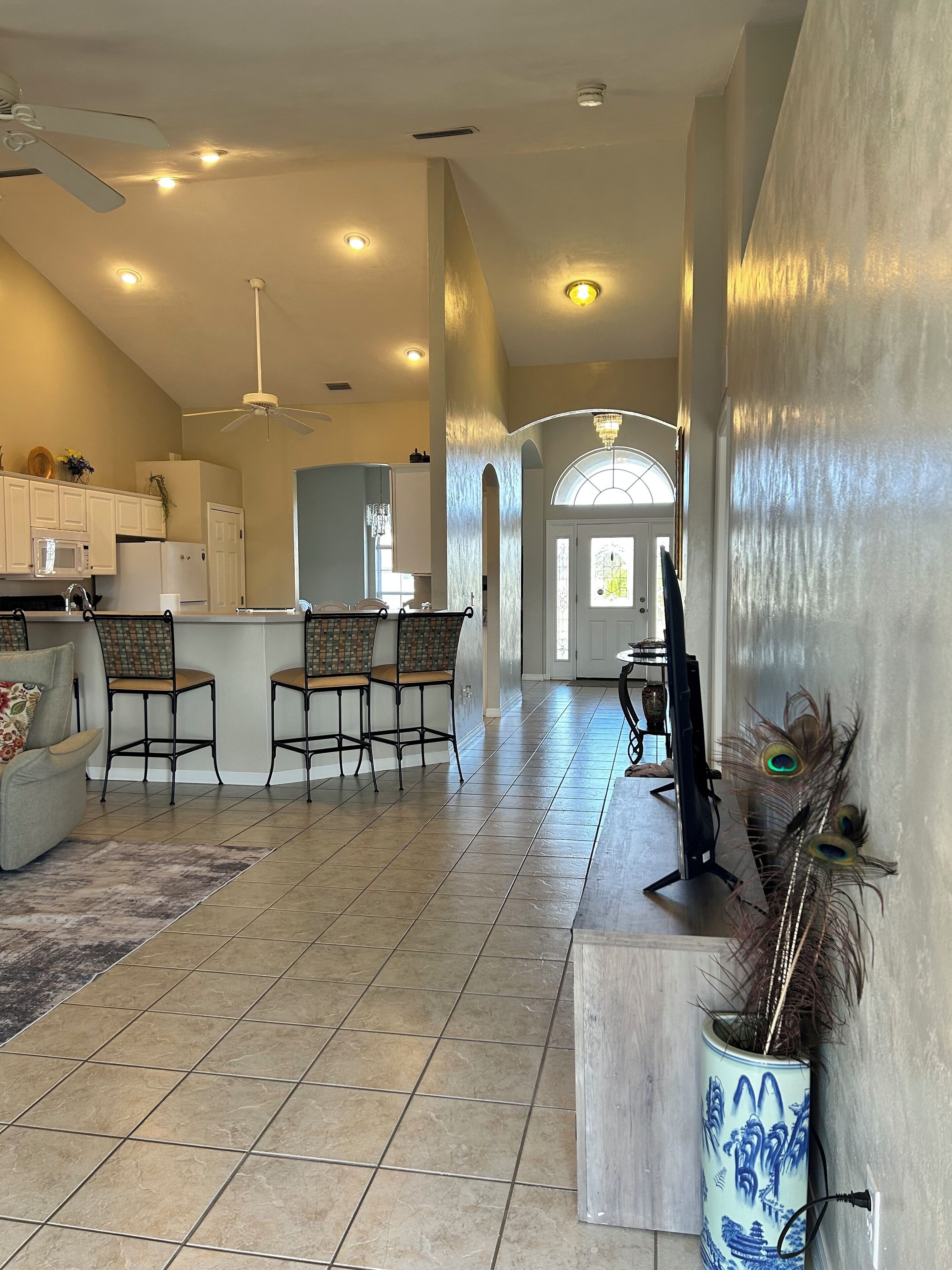 A spacious living area with a kitchen, dining area, and a hallway leading to a door.