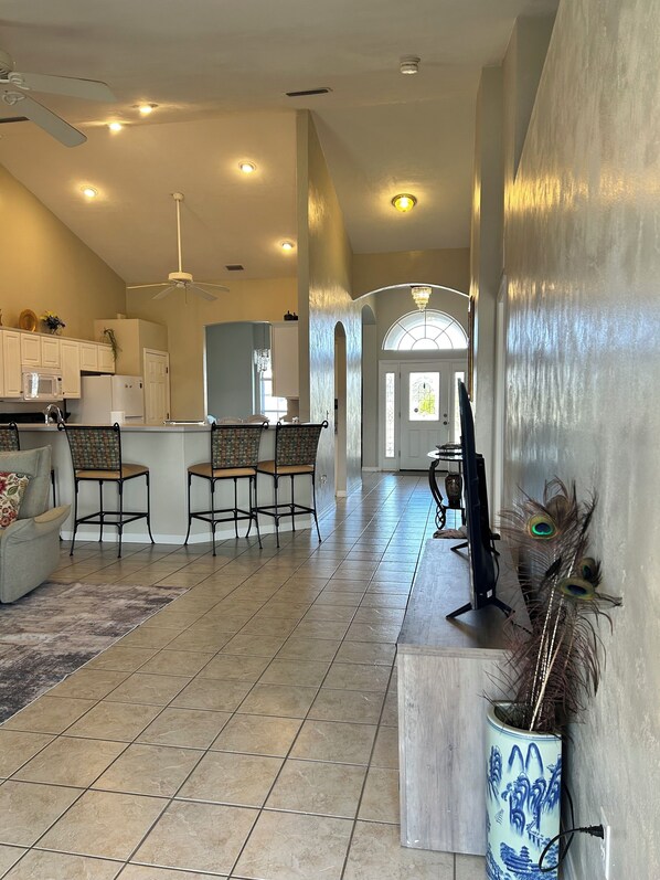 A spacious living area with a kitchen, dining area, and a hallway leading to a door.