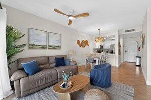 A modern living room with a sofa, coffee table, and a ceiling fan. - Sunny Naples Getaway- 2BR Condo with Pool, Tennis, & Minutes to Beach (Naples)