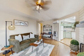 A living room with a sofa, coffee table, and floor lamp. There is a kitchen visible in the background. - Tranquil Banner Elk Escape | Views, Pool & Slopes (Banner Elk)