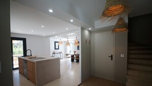 Una cocina moderna con una isla central, un comedor con sillas y una escalera que lleva a otro nivel.