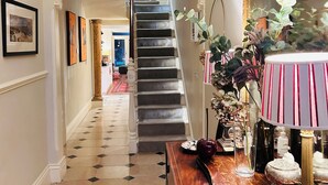 Eine prächtige Diele mit Treppe, einem Holzkonsole und dekorativen Accessoires sowie einem großen Spiegel.