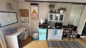 A compact kitchen with a microwave, toaster, and small refrigerator. There's a whiteboard with notes, a small desk with a chair, and a striped rug on the floor. - Adorable bungalow with AC in charming Glendale perfect for relaxing (Glendale)