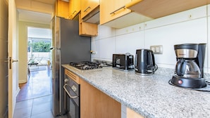A modern kitchen with wooden cabinets, a gas stove, a toaster, a coffee maker, and a refrigerator. - 2-bedroom apartment in peaceful Providencia with AC and charm (Providencia)