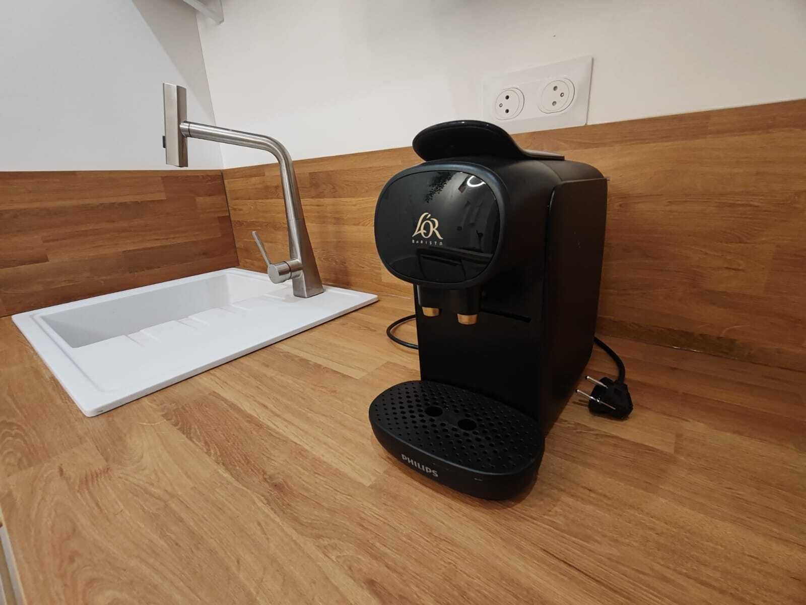 A modern kitchen with a built-in coffee maker, a sink, and a wooden backsplash.