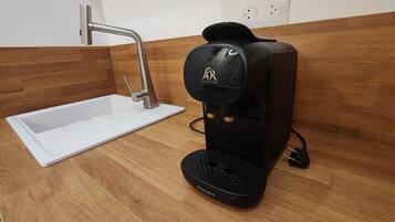 A modern kitchen with a built-in coffee maker, a sink, and a wooden backsplash.