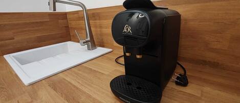 Eine moderne Küche mit integriertem Kaffeeautomaten, einer Spüle und einer Holzrückwand.