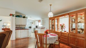 A spacious kitchen with wooden cabinets, a dining table with chairs, and a chandelier. - Fork River Getaway in Stuart: 6 Mi to Downtown! (Stuart)