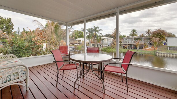 A covered outdoor area with a round table and four chairs, overlooking a body of water and a residential area. - Fork River Getaway in Stuart: 6 Mi to Downtown! (Stuart)