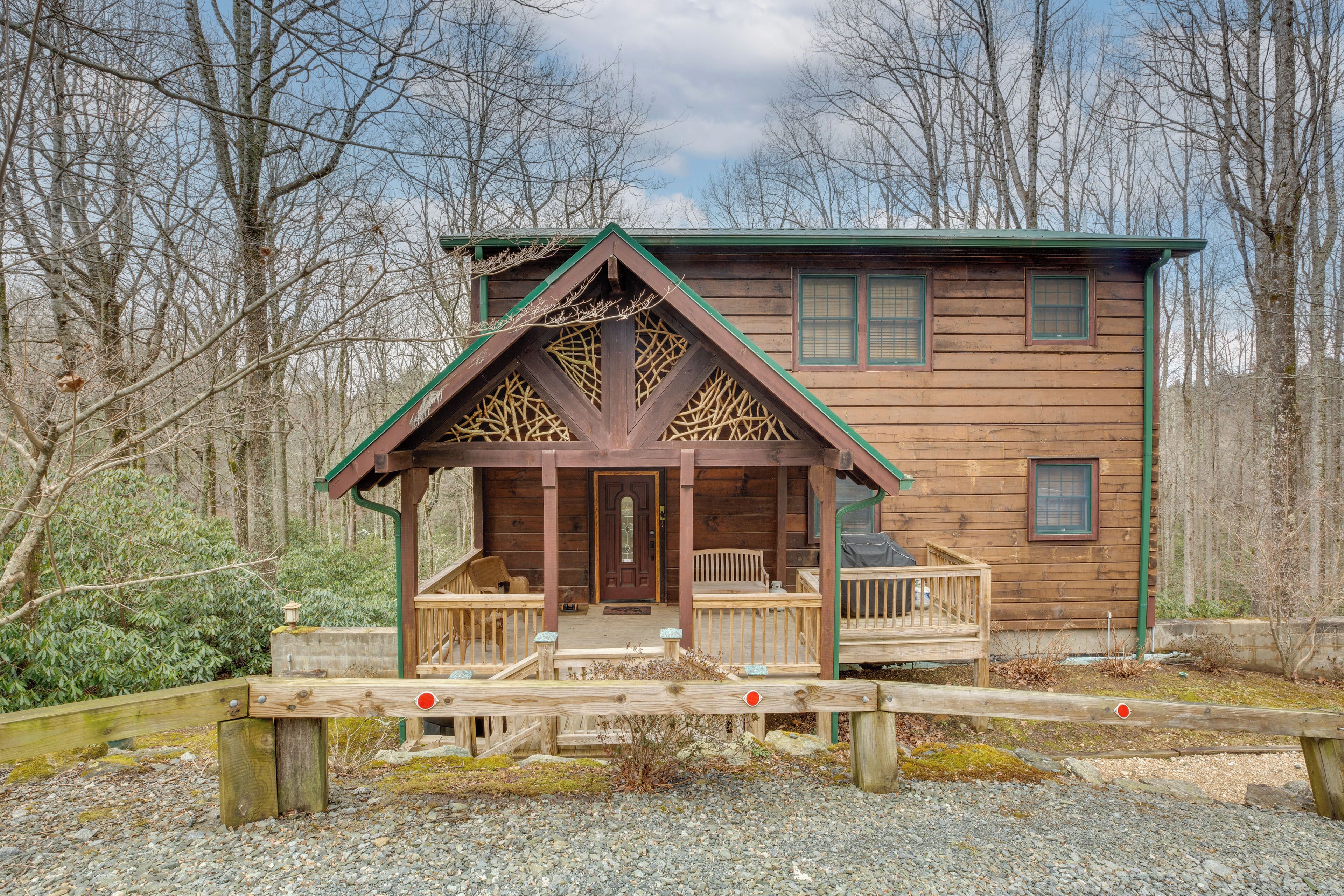 A wooden cabin with a porch, surrounded by trees.