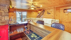 Un interior de madera con una zona de bar, asientos y una escalera.
