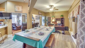 A spacious dining area with a long table set for a meal, a ceiling fan, and a television in the background. - Explore Gulf Coast & Beyond! Home w/ Yard & Games (Long Beach)