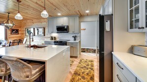 A kitchen with wooden ceiling, white cabinets, a central island, and a refrigerator.