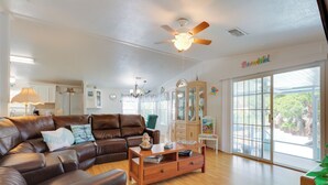A spacious living room with a brown leather sofa, wooden coffee table, and a ceiling fan.