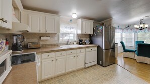 A kitchen with white cabinets, a stainless steel refrigerator, a coffee maker, and a toaster.