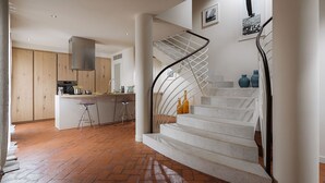 Een moderne keuken met een centraal eiland, een trap met een metalen leuning en een visgraatvloer.