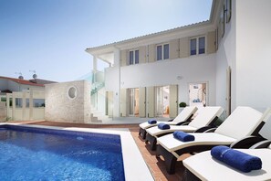Ein moderner Poolbereich mit Liegestühlen und einem klaren, blauen Pool.