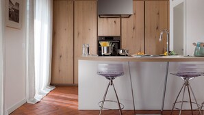 Een moderne keuken met houten kastjes, een centraal eiland met barstoelen, roestvrijstalen apparatuur en een hanglamp.