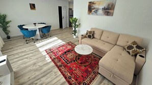 A modern living room with a beige sofa, a red patterned rug, and a blue chair. - Cozy 1-bedroom apartment in Downtown beautiful San Diego with AC (San Diego)
