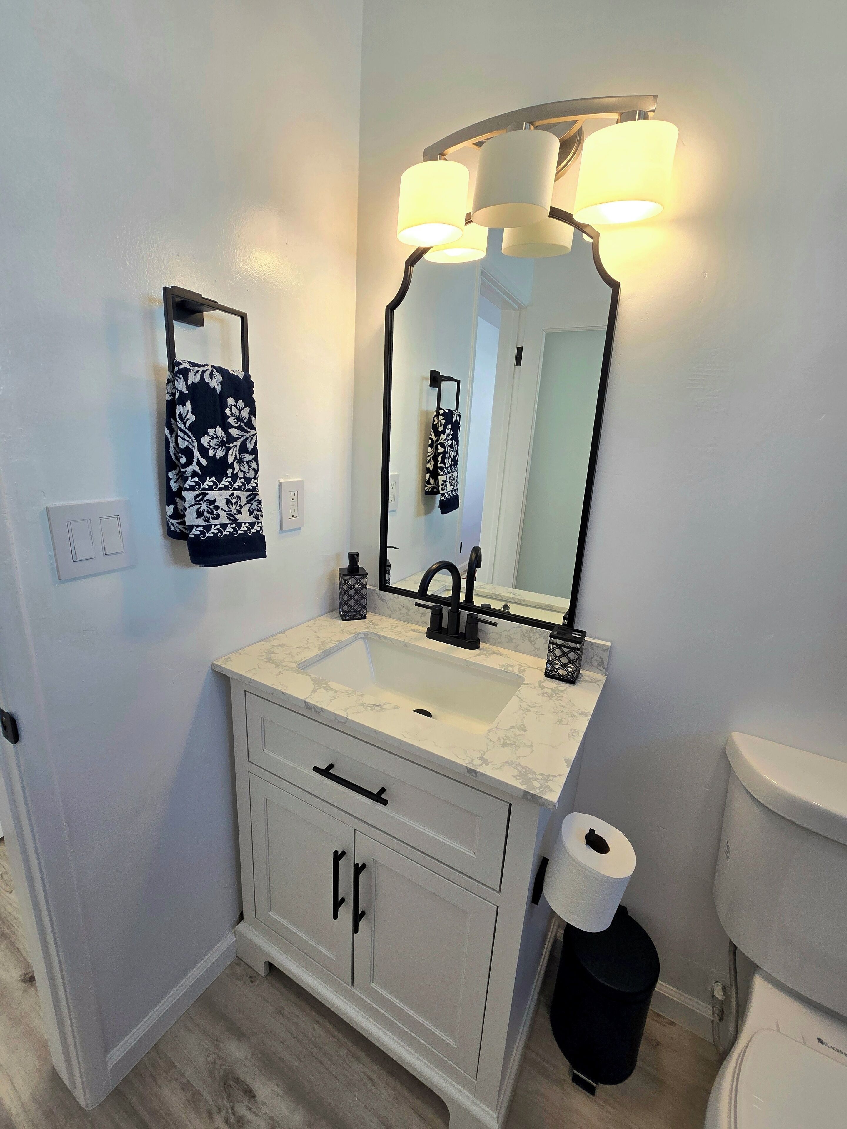 A bathroom with a white vanity, a mirror, a sink, and a toilet.