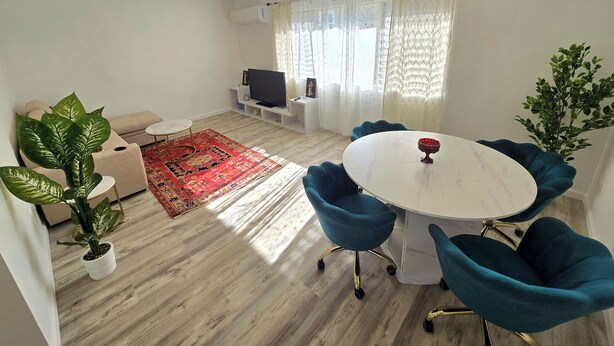 A modern living room with a sofa, a TV, a dining table with chairs, and a potted plant. - Cozy 1-bedroom apartment in Downtown beautiful San Diego with AC (San Diego)