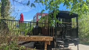 Un andén de estación de tren con un tren, un paraguas rojo y follaje.