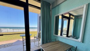 Un balcón con mesa y sillas, vista a la playa y un letrero de 'No Fumar'.