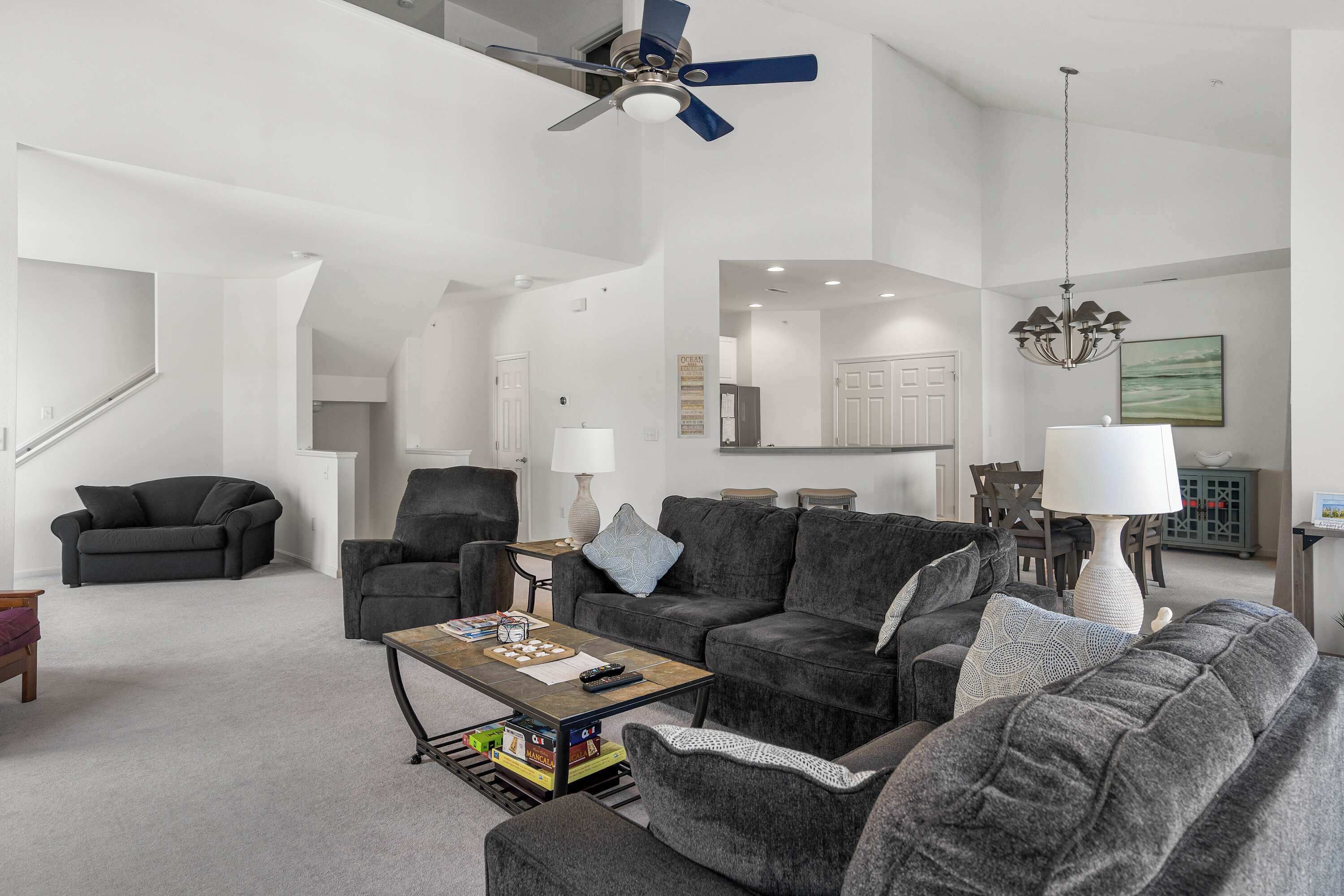 A modern living room with a sectional sofa, a coffee table, and a ceiling fan.