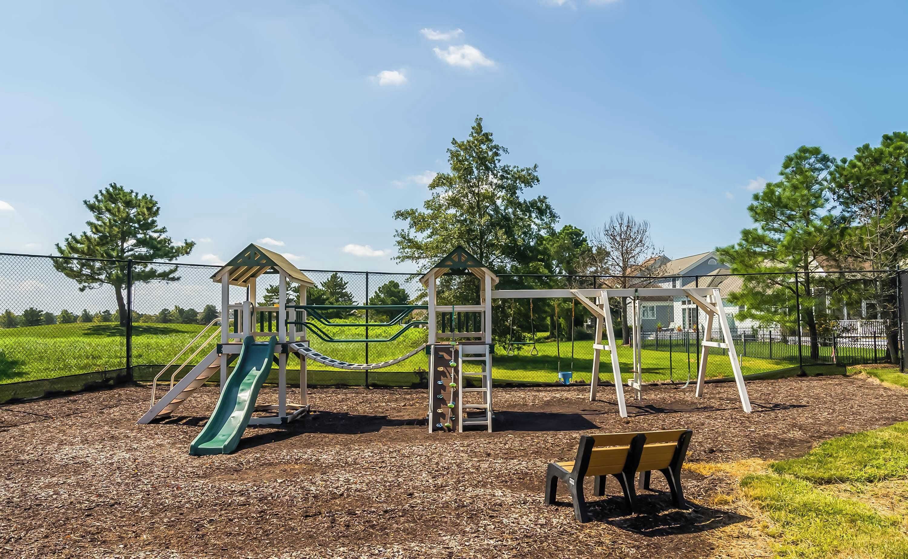 A playground with a slide, climbing wall, and swings.