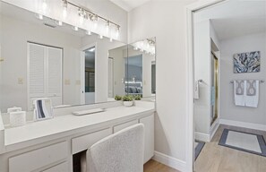Une salle de bain moderne avec un grand miroir, un meuble-lavabo blanc et un espace douche.