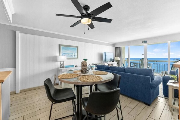 Una sala de estar moderna con una mesa redonda, sofá azul y ventilador de techo.