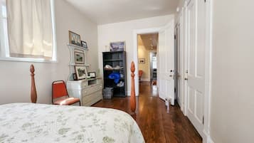 A bedroom with a bed, a dresser, a chair, a bookshelf, and a door leading to another room.