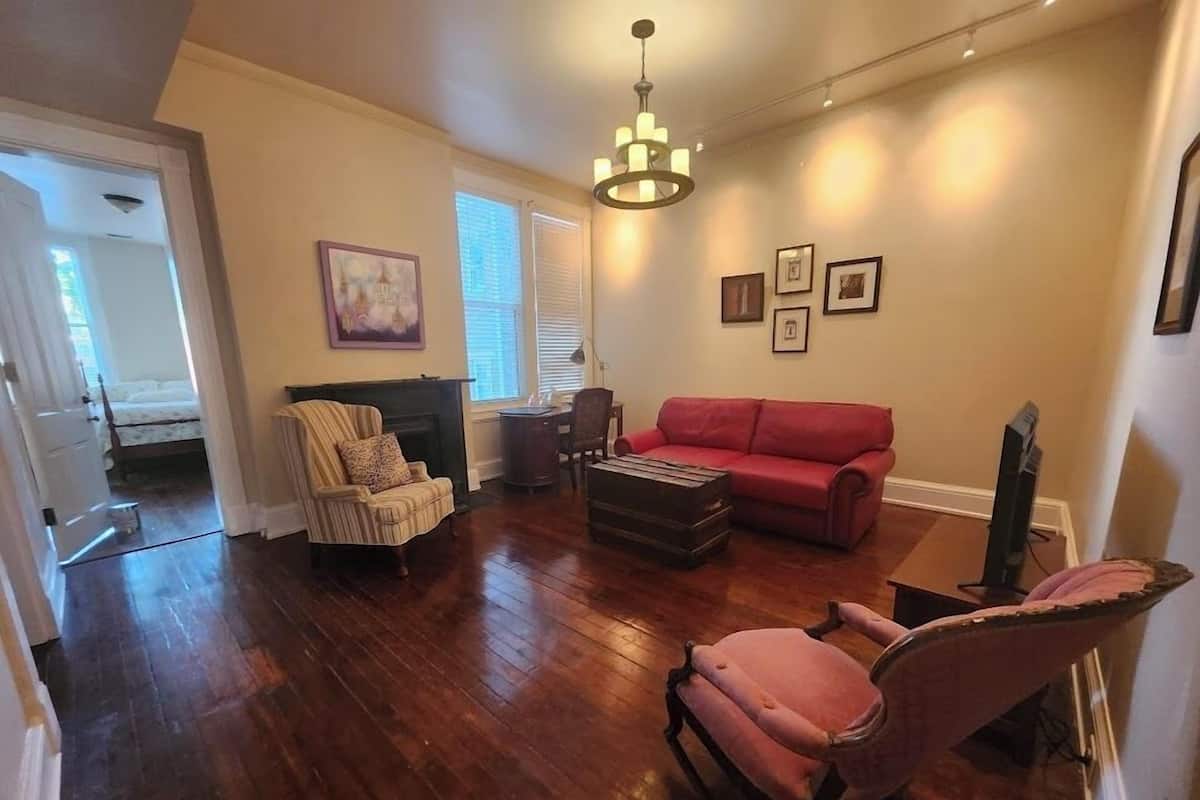 Una sala de estar con chimenea, un sofá rojo, un sillón rosa y un televisor.