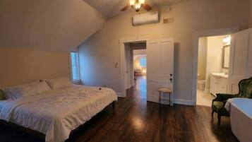 A bedroom with a bed, a ceiling fan, and a door leading to a bathroom.