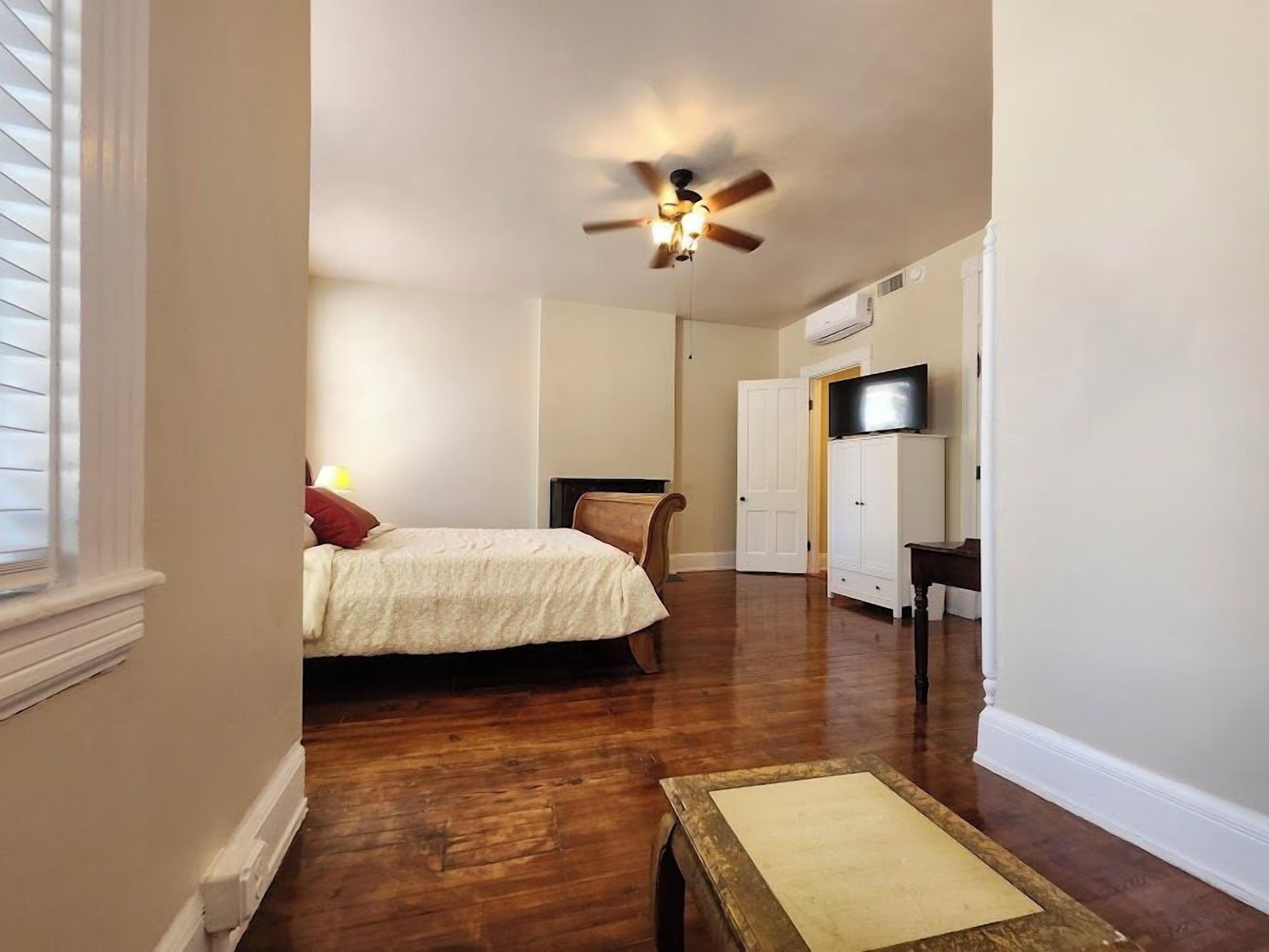 A bedroom with a bed, a ceiling fan, a TV, and a wardrobe.