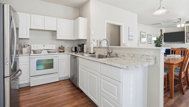 A modern kitchen with white cabinetry, a built-in oven, a dishwasher, and a granite countertop. - Home Away from Home (Fort Worth)