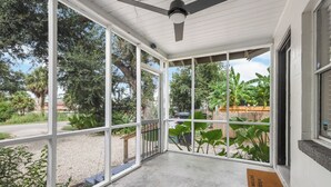 Ein überdachter Balkon mit großen Fenstern, einem Deckenventilator und einer Fußmatte.