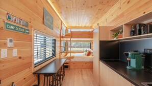 A compact cabin with a bunk bed, a kitchenette, and a dining area.