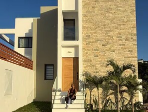 Un edificio moderno con una scala che conduce a una porta di legno, circondato da palme.
