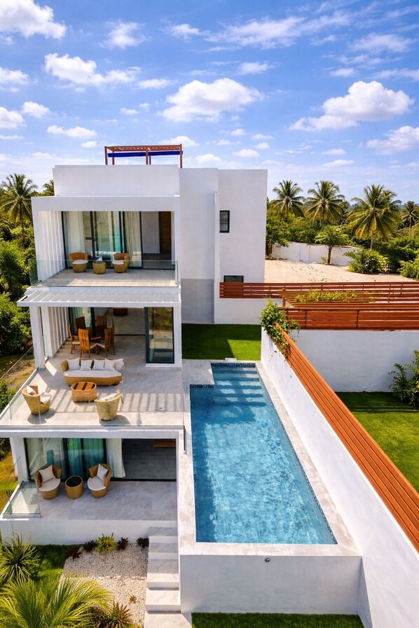 A modern two-story house with a swimming pool, outdoor seating, and a view of palm trees. - 3-bedroom villa in fabulous Las Terrenas with AC (Las Terrenas)