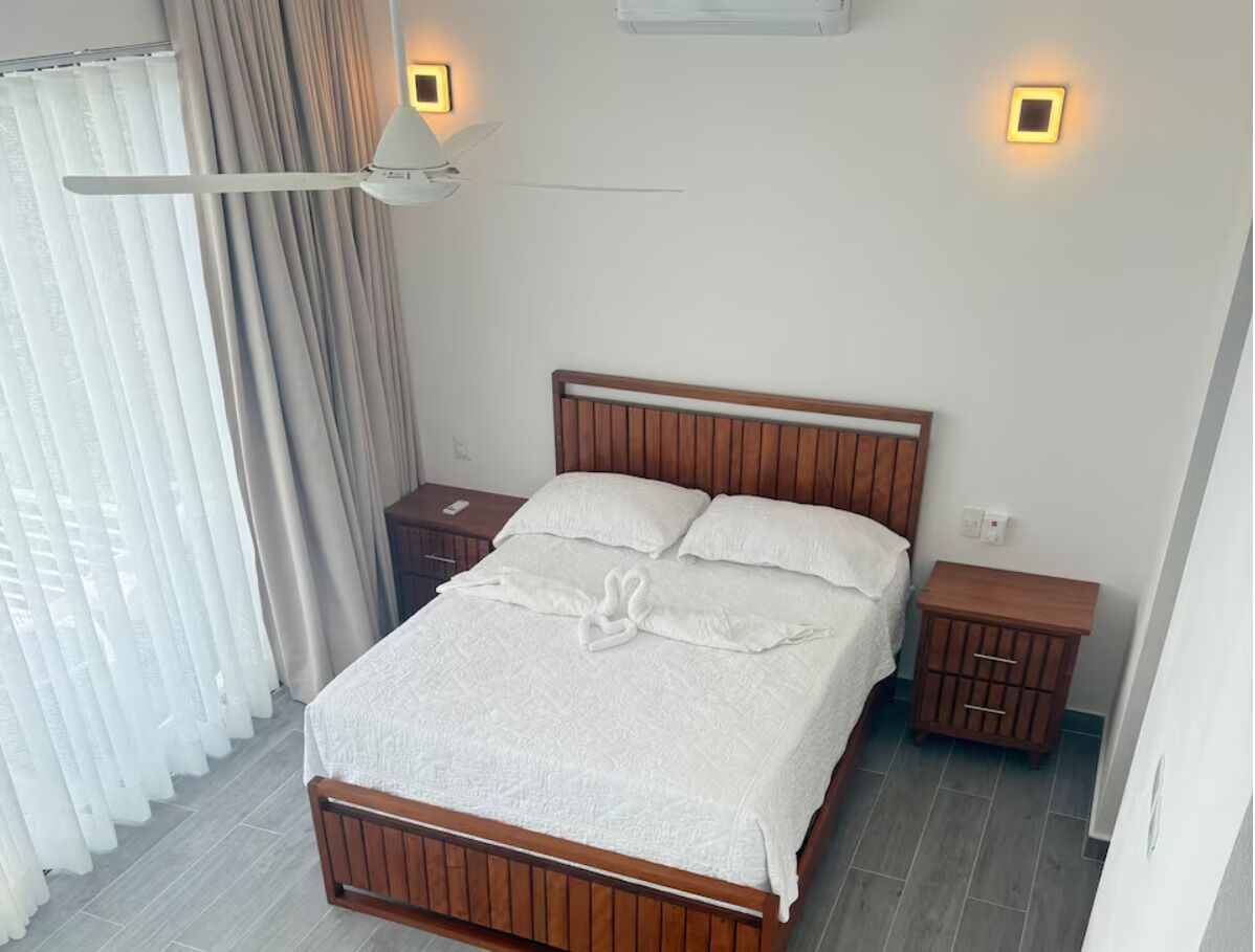 A neatly made bed with a wooden headboard, two bedside tables, and a ceiling fan.