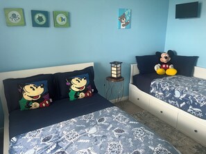 A bedroom with two beds, a nightstand, a lamp, and wall art. - Less Stress Express ; A trip to your wants & Needs (osceola)