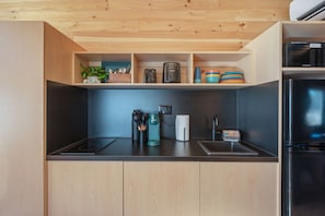 A modern kitchen with wooden cabinets, a black countertop, a built-in stove, and a microwave. - Waterfront Access Private Hot tub Yard 9 (Fort Walton Beach)