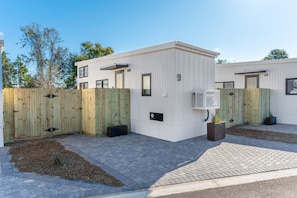 A modern building with a white exterior, a wooden fence, and a paved driveway. - Waterfront Access Private Hot tub Yard 9 (Fort Walton Beach)