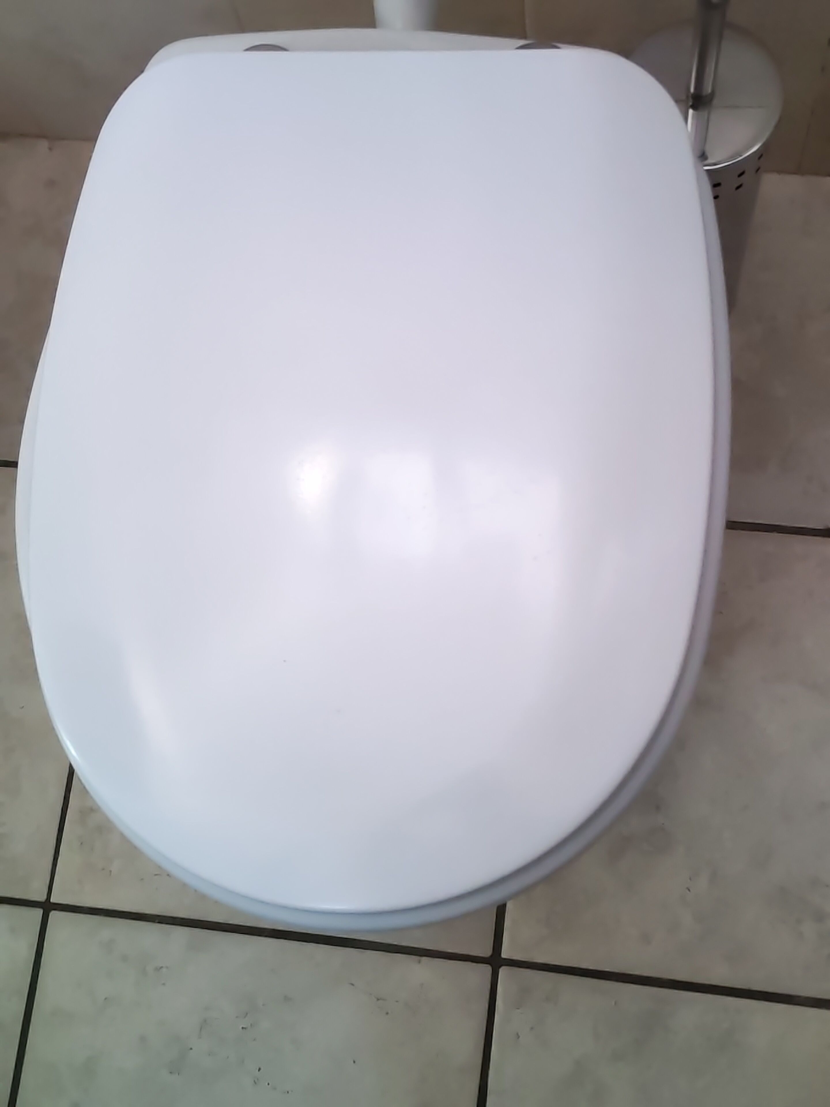 Un water bianco in un bagno con pavimento piastrellato.