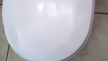 Un water bianco in un bagno con pavimento piastrellato.