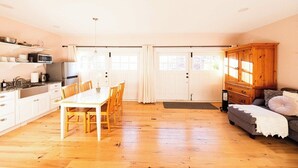 Un vaste espace de vie comprenant une table et des chaises en bois pour les repas, un canapé et un meuble.